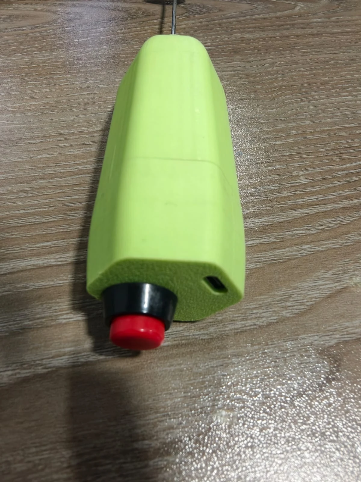 Close photograph of the prototype's button end: red push button with black bezel and the USB-C opening on a flat of the housing